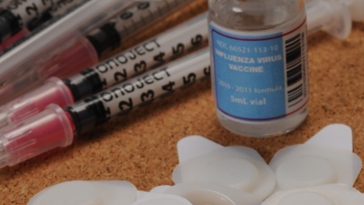 Ten microneedle patches are shown with a ten-dose vial of influenza vaccine and ten hypodermic needles with syringes. (Georgia Tech Photo: Gary Meek)
