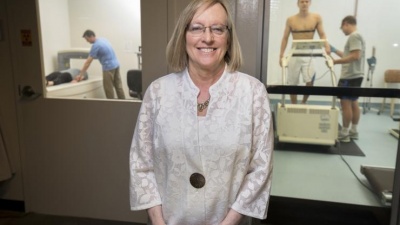 Professor Mindy Millard-Stafford researches in exercise physiology, including studies on how dehydration and exertion can reduce physical and cognitive performance. In the background, a volunteer lies on a device that measures body composition (l.) and another volunteer sweats out fluids under exertion in a heated chamber (r.). Millard-Stafford is Past President of the American College of Sports Medicine. Credit: Georgia Tech / Christopher Moore