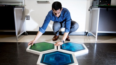 Ilan Stern, a GTRI senior research scientist, shows piezoelectric tiles that will be used to create a lighted outdoor footpath at the NASA Kennedy Space Center’s Visitor Complex at Cape Canaveral, Florida. He’s holding the electronic components used in the tiles. (Credit: Branden Camp, Georgia Tech)