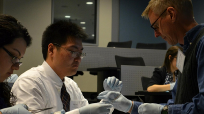 Dr. Holton teaches students basic skills in suturing using pigs' feet.