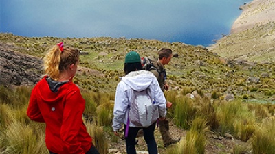 Georgia Tech students hike down a mountain towards a blue lake.