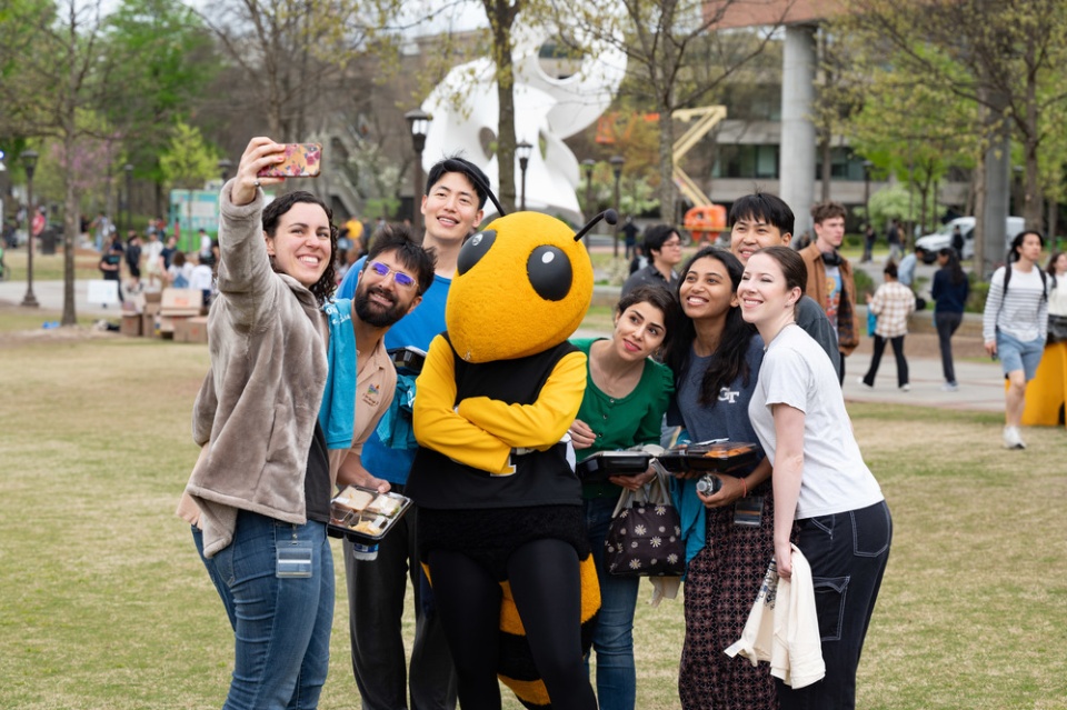 Georgia Tech students pose with Buzz on Tech Green. 