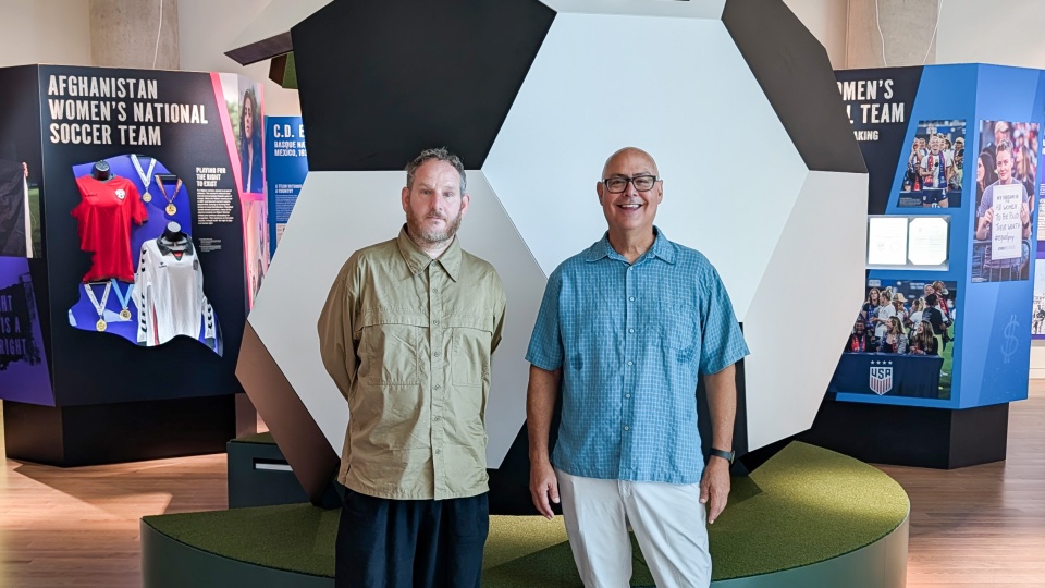 Two men stand in front of a soccer-ball shaped exhibit at the National Center for Civil and Human Rights.